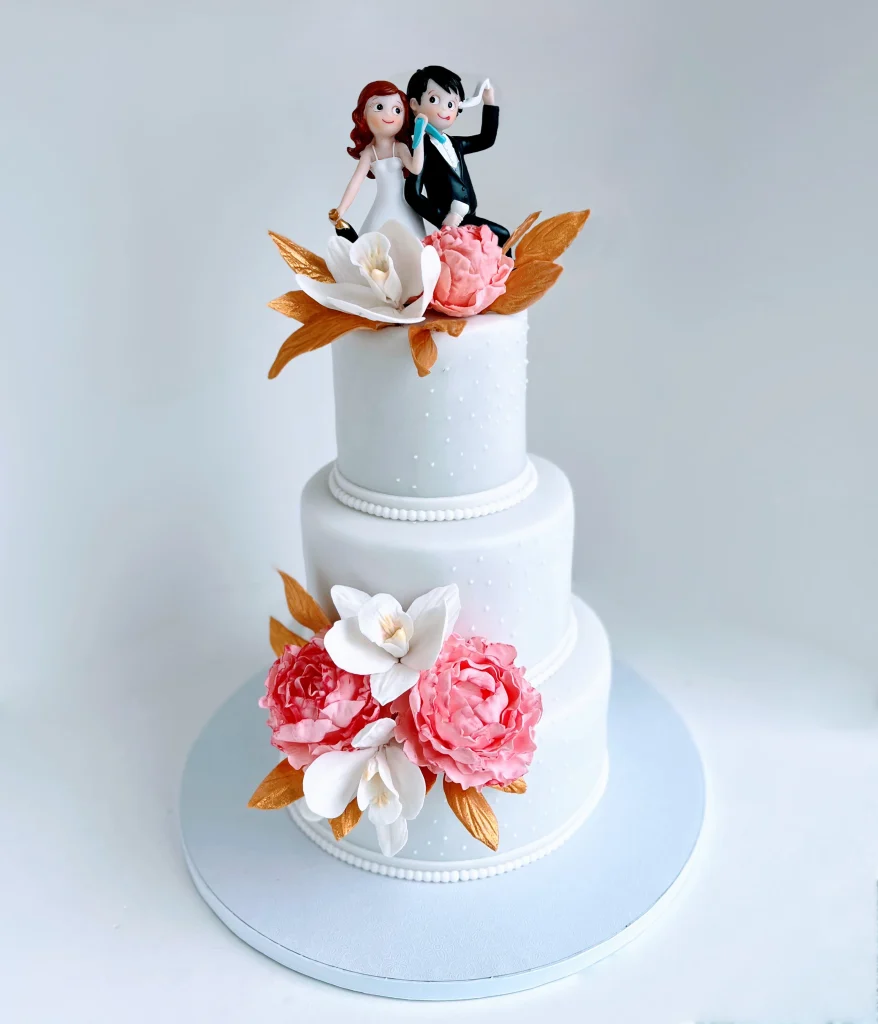 Three-Tiered Wedding Cake with Fondant Flowers and Resin Bride and Groom Figures.